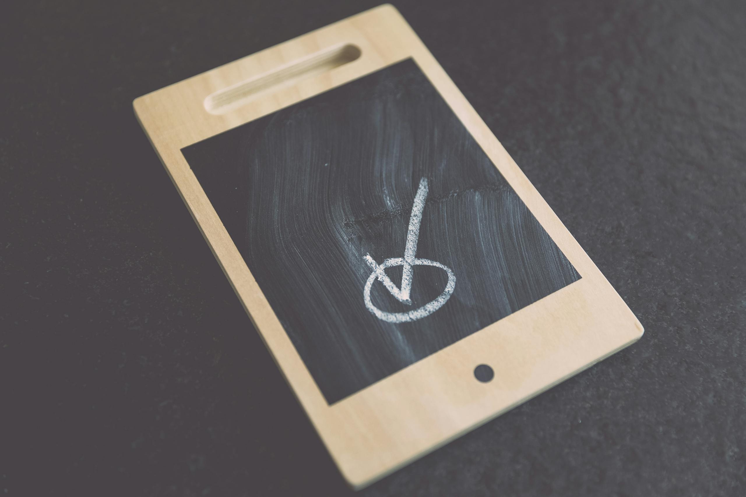 Small wooden chalkboard tablet with a checkmark drawn on it, suitable for concepts like success and approval.